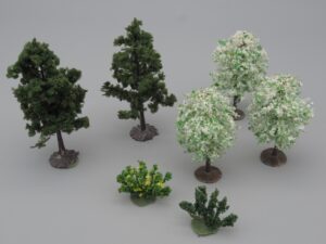 5 arbres verts et blancs et 2 arbustes